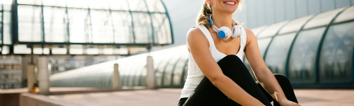 Vrouw in sportkleding strikt veters en draagt koptelefoon