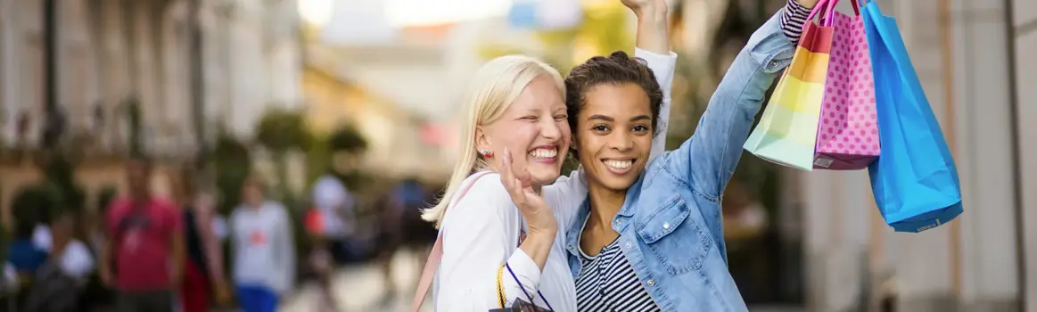 Twee vrouwen aan het winkelen met shopping bags in een winkelstraat