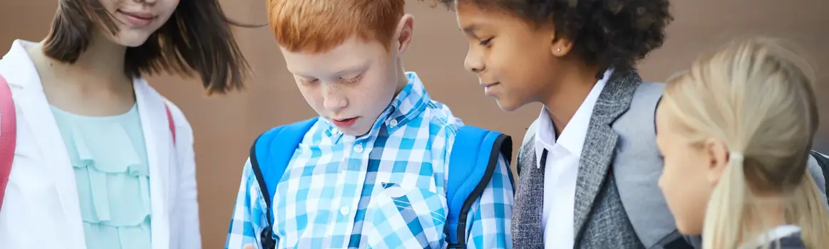 Vier jonge kinderen die samen kijken naar een telefoonscherm