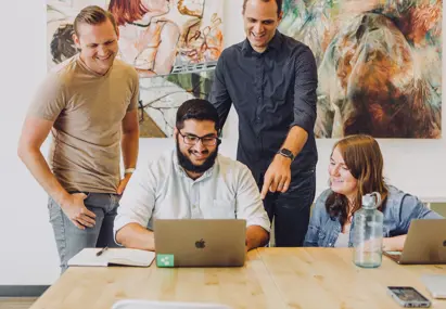 vier collega's lachend achter een laptop