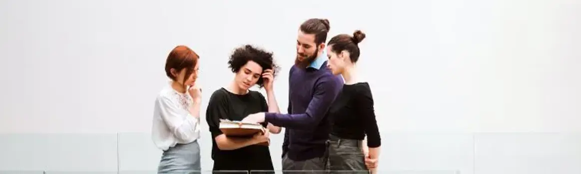 Vier personen in gesprek voor een hoge witte muur
