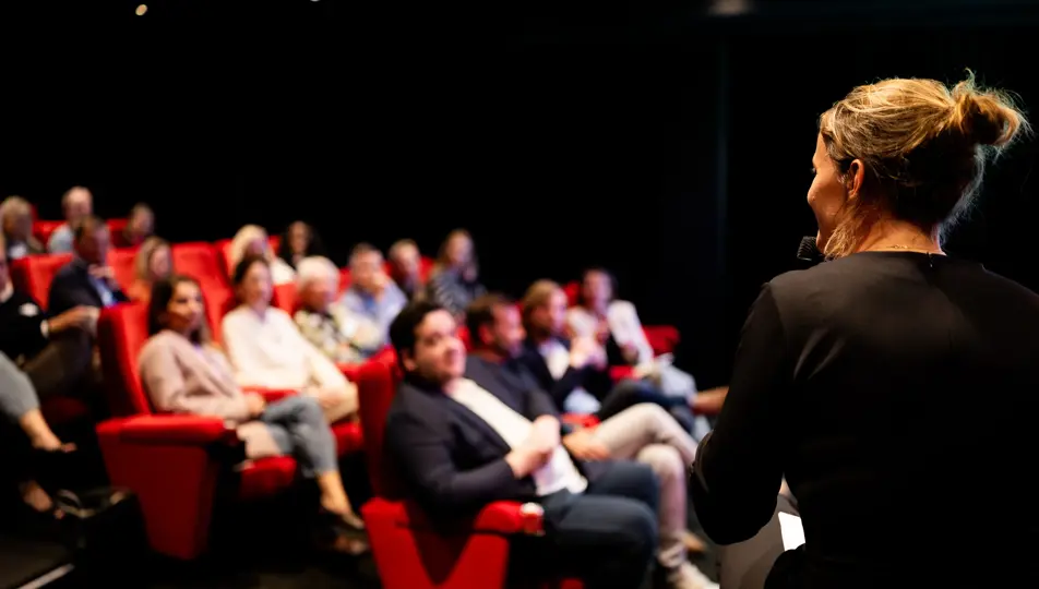 Achterkant presentator en geblurd aanzicht van aanwezigen tijdens bvA event