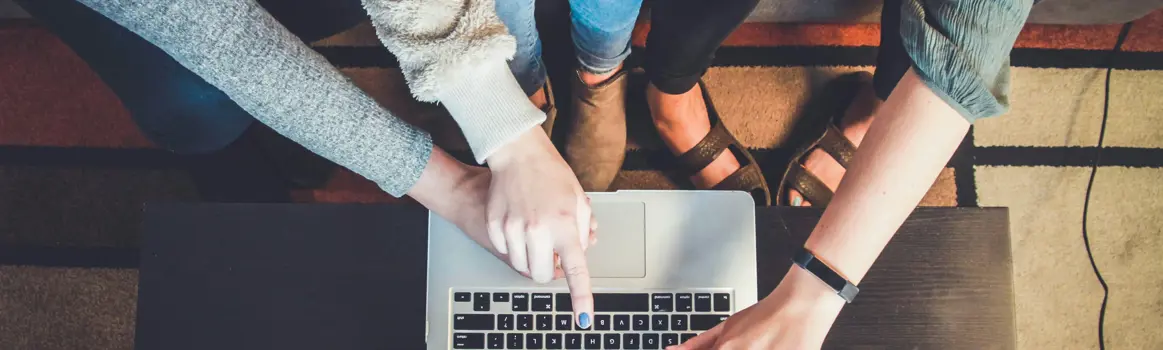Verschillende personen kijken en wijzen naar een laptop