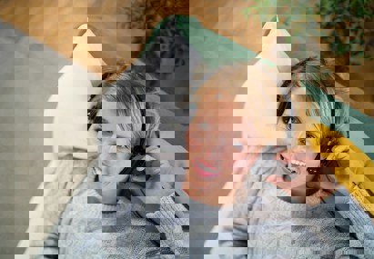 Vrouw luistert ontspannen naar audio via koptelefoon op de bank