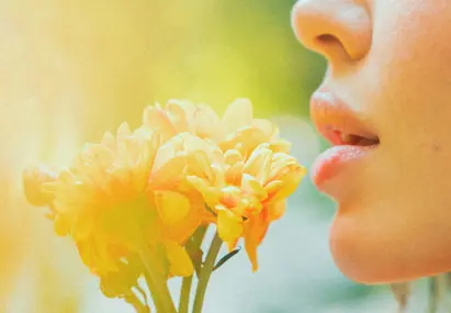 Vrouw ruikt aan gele bloemen