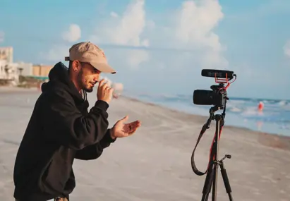 Man met videocamera op strand