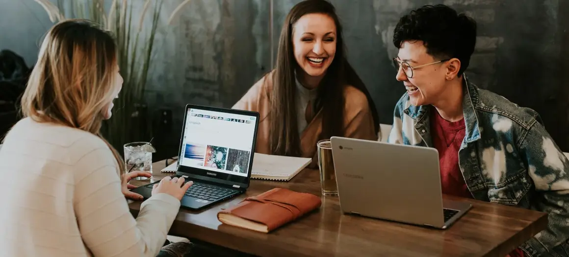 Drie vrouwen aan tafel met ieder een eigen laptop
