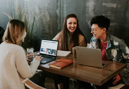Drie vrouwen aan tafel met ieder een eigen laptop